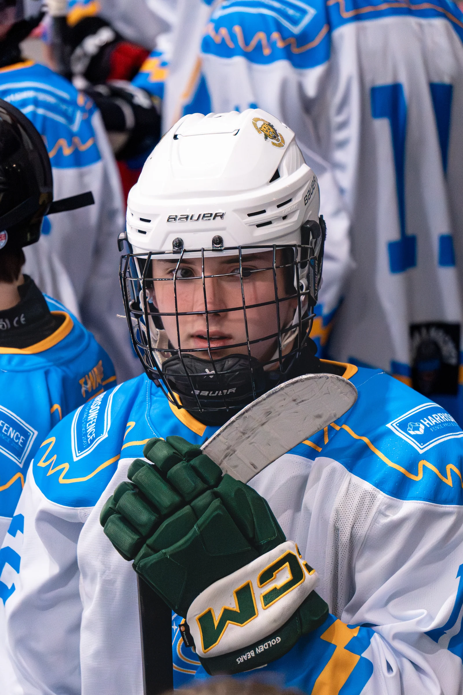 Wake Forest youth hockey player in a white helmet holding a stick during a bench portrait